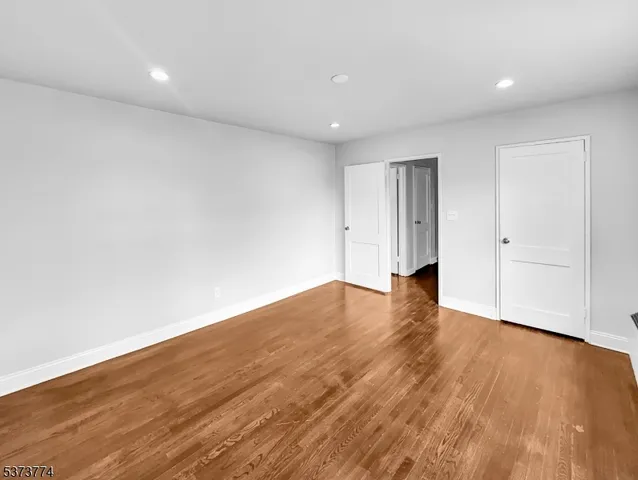 a view of empty room with wooden floor and white doors