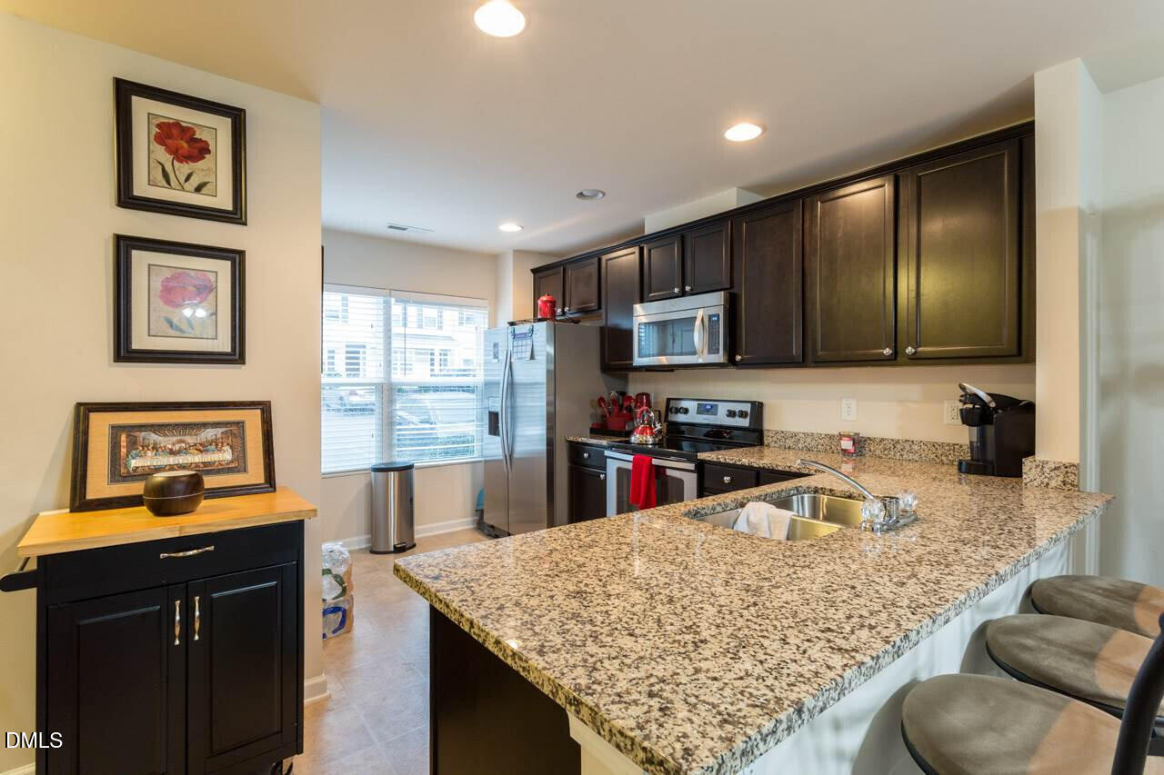 4009 Tresco Crossing Raleigh, NC 27616 - Photo 12 of 23 a kitchen with stainless steel appliances granite countertop a sink refrigerator stove and microwave