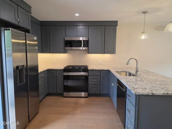 a kitchen with stainless steel appliances granite countertop a refrigerator and a sink