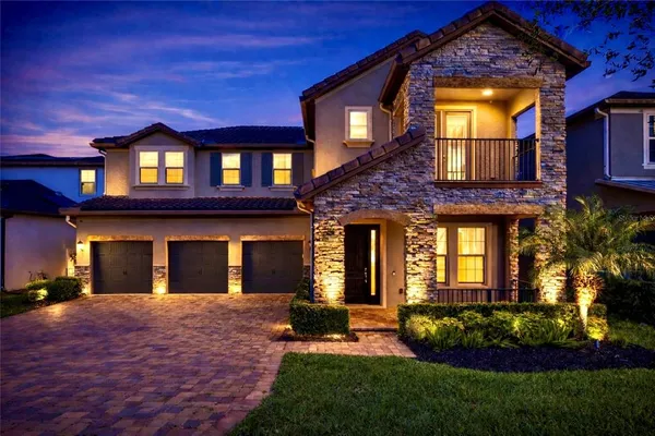 a view of a brick house with a large windows and a yard with plants and large tree