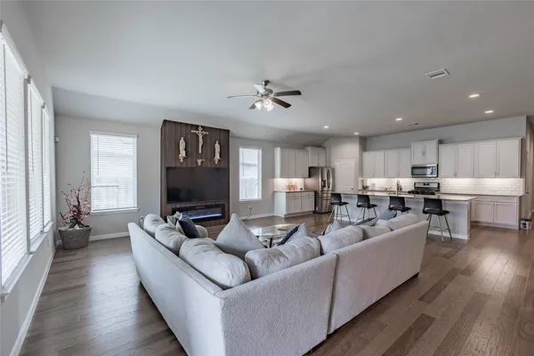 a living room with furniture kitchen view and a wooden floor