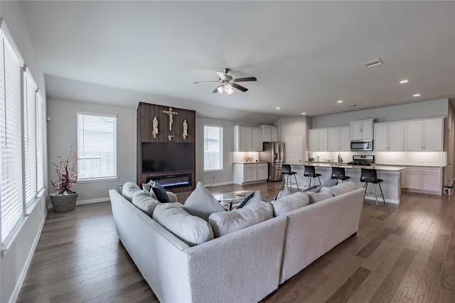a living room with furniture kitchen view and a wooden floor