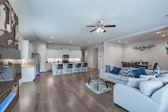 a living room with furniture kitchen view and a wooden floor