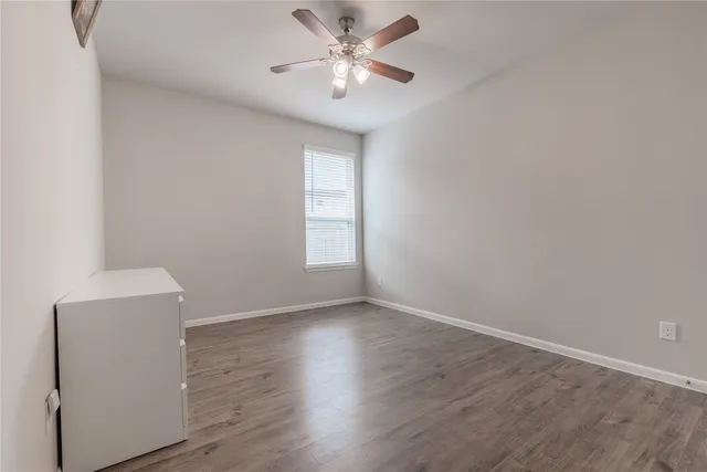 an empty room with wooden floor and a ceiling fan