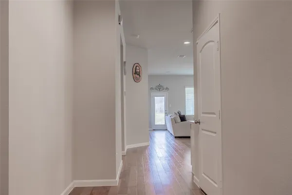 a view of a hallway with wooden floor and a living room