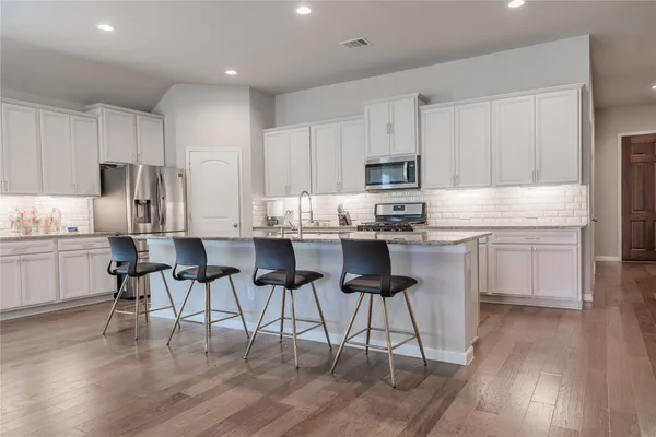 a kitchen with cabinets wooden floor and stainless steel appliances