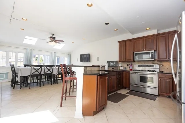 a kitchen with stainless steel appliances kitchen island granite countertop a stove top oven a sink dishwasher a dining table and chairs