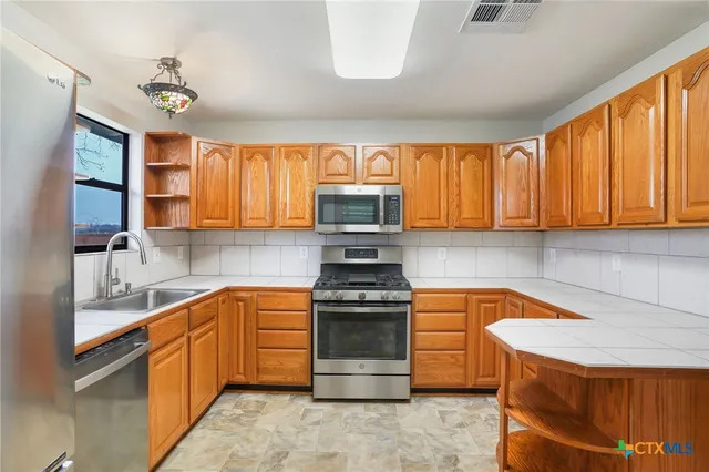 a kitchen with stainless steel appliances granite countertop a stove a sink and a microwave