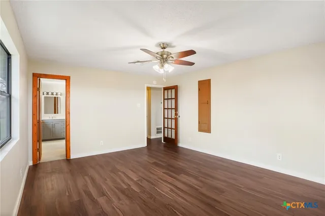 a view of an empty room with a window and wooden floor