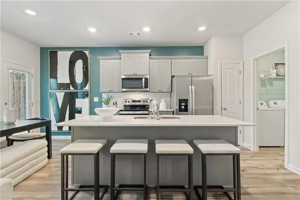 a kitchen with stainless steel appliances granite countertop a table chairs refrigerator and microwave