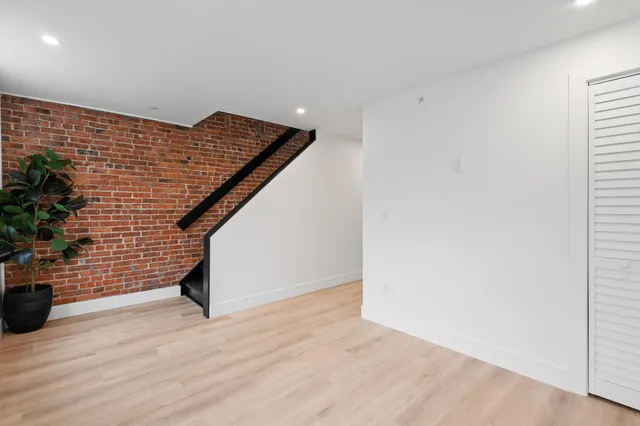 a view of an empty room with wooden floor and a potted plant