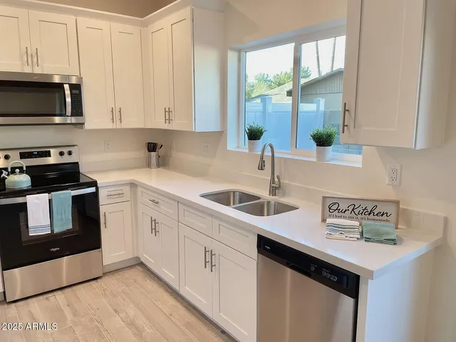 a kitchen with stainless steel appliances a refrigerator a stove top oven a sink and dishwasher