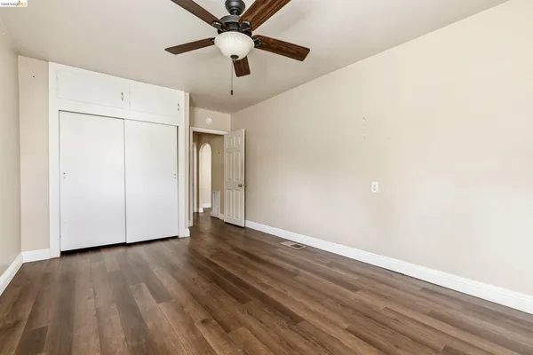 an empty room with wooden floor fan and windows