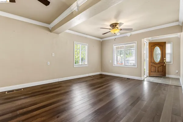 a view of an empty room with a window and wooden floor