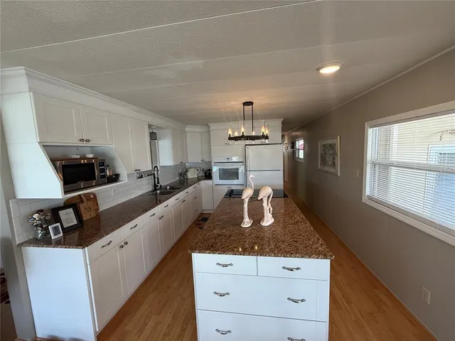 a large kitchen with granite countertop a sink counter top space and stainless steel appliances