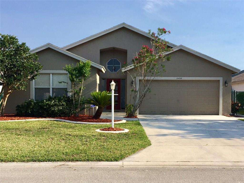 2498 Southwest Regency Road Stuart, FL 34997 - Photo 1 of 47 a front view of a house with garden