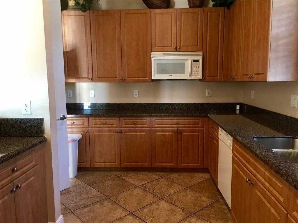 2498 Southwest Regency Road Stuart, FL 34997 - Photo 40 of 47 a kitchen with granite countertop a stove top oven microwave and cabinets