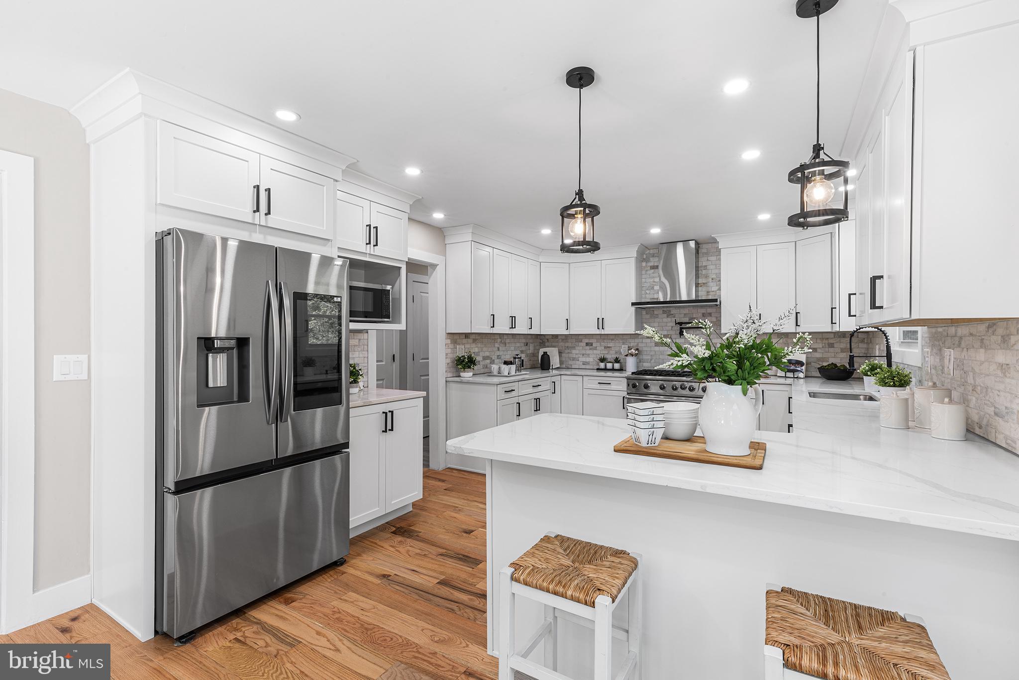 849 Glenn Circle Wayne, PA 19087 - Photo 2 of 36 a kitchen with stainless steel appliances granite countertop a refrigerator a sink dishwasher a oven a dining table and chairs with wooden floor