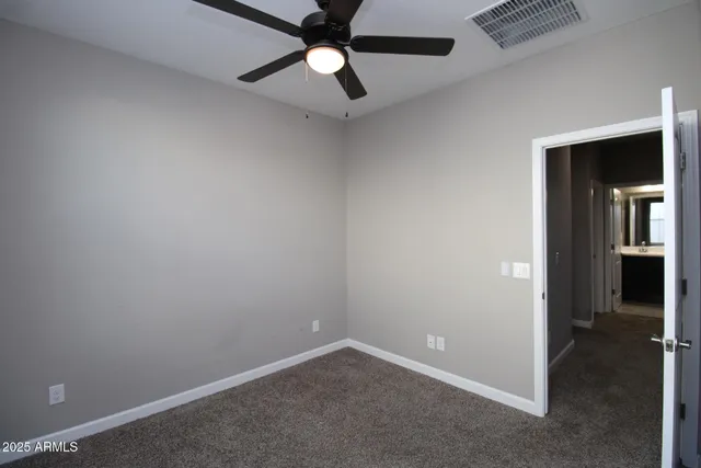 en empty room with closet and a chandelier fan