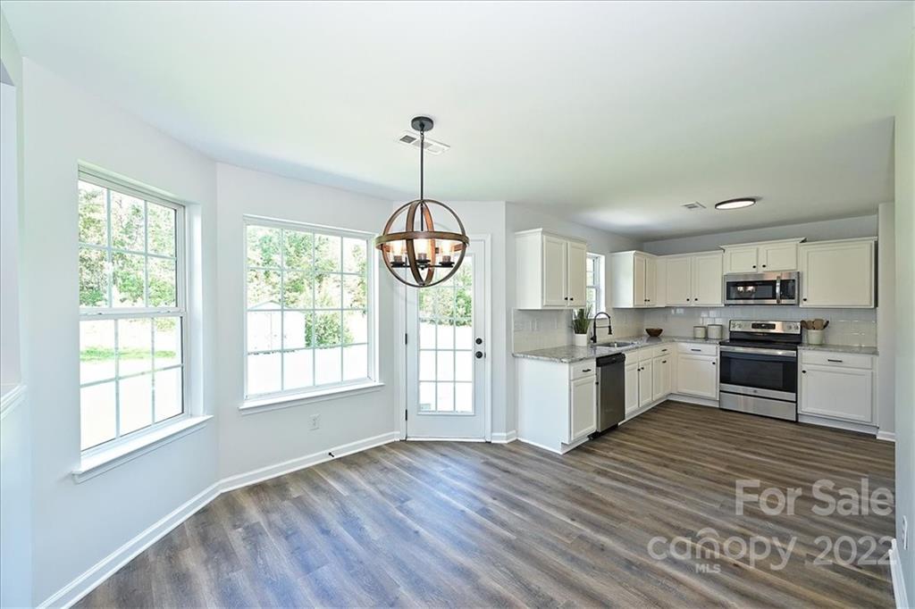 675 Winding Branch Road Rock Hill, SC 29732 - Photo 8 of 34 a kitchen with granite countertop wooden floors stainless steel appliances and white cabinets