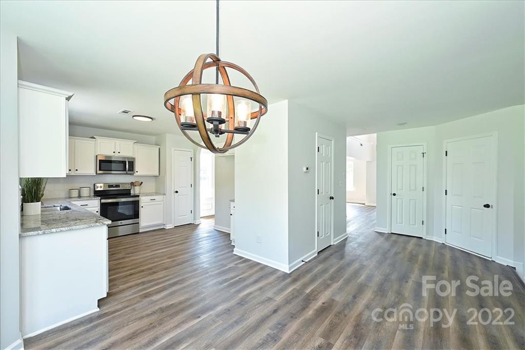 675 Winding Branch Road Rock Hill, SC 29732 - Photo 10 of 34 an empty room with wooden floor kitchen view and a chandelier