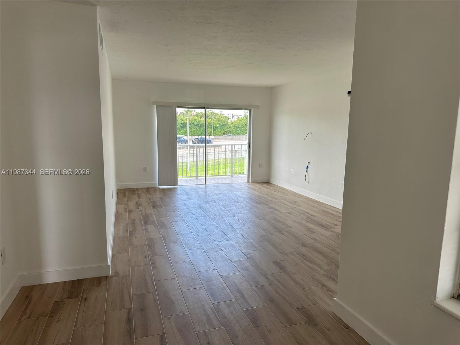 7670 Southwest 82nd Street, Unit H215 Miami, FL 33143 - Photo 2 of 9 a view of an empty room with wooden floor and a window