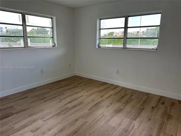 an empty room with wooden floor and windows