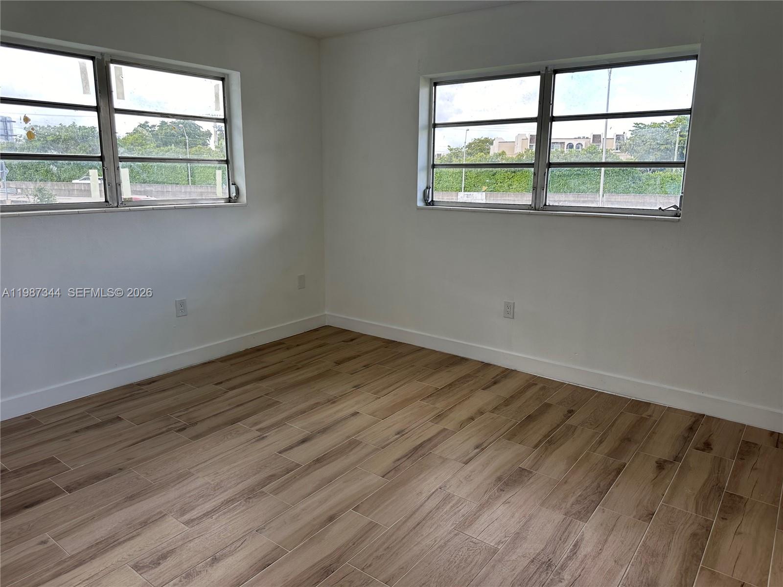 7670 Southwest 82nd Street, Unit H215 Miami, FL 33143 - Photo 4 of 9 an empty room with wooden floor and windows