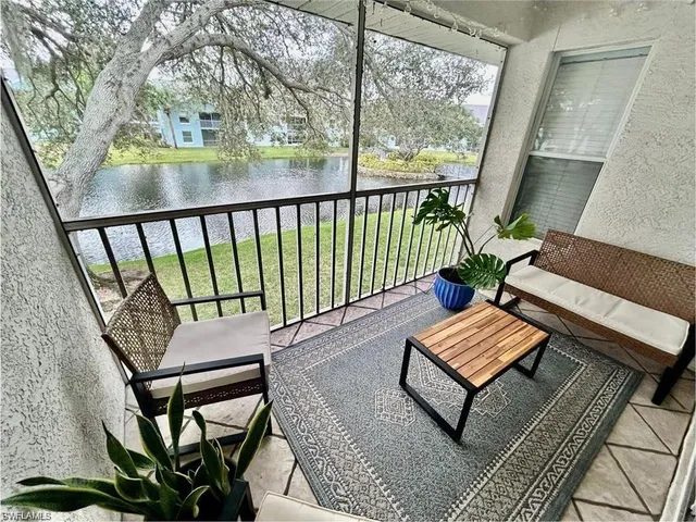 a balcony with couple of chairs and a potted plant on a table