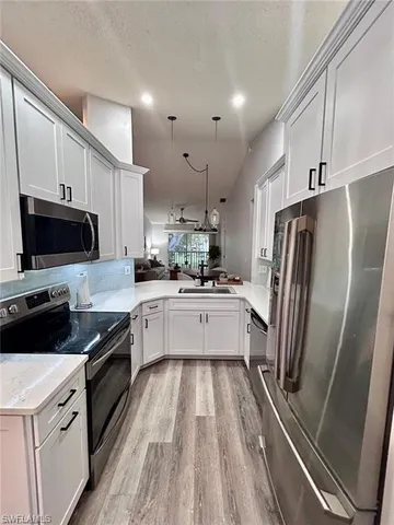 a large kitchen with a refrigerator a microwave a sink and cabinets