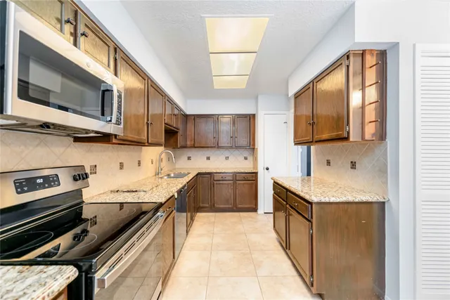 a kitchen with stainless steel appliances granite countertop a stove a sink and a microwave