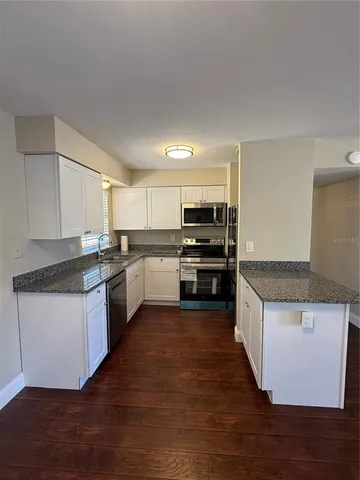 a kitchen with granite countertop a stove top oven and cabinets