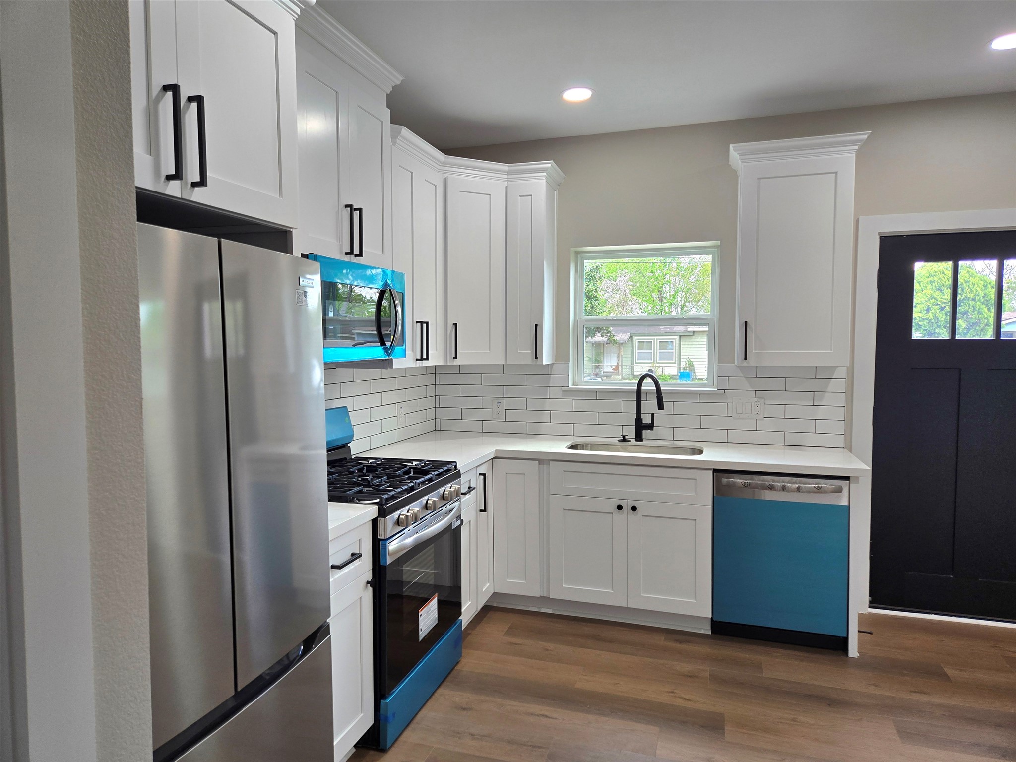 7830 Woodlyn Road, Unit B Houston, TX 77028 - Photo 3 of 10 Another view of the updated kitchen showcasing white cabinetry, stainless appliances, and a bright, modern layout.