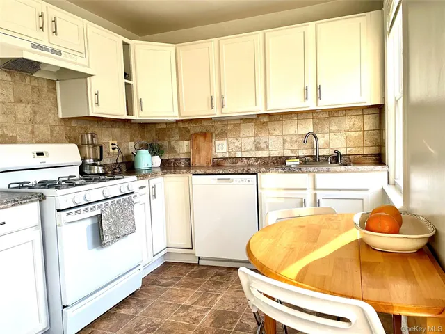 a kitchen with granite countertop white cabinets and white appliances