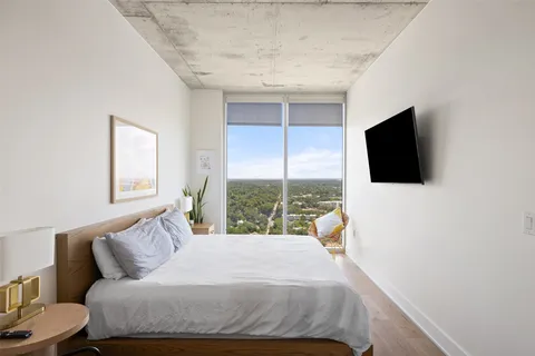 a bedroom with a bed outdoor view and a flat tv screen