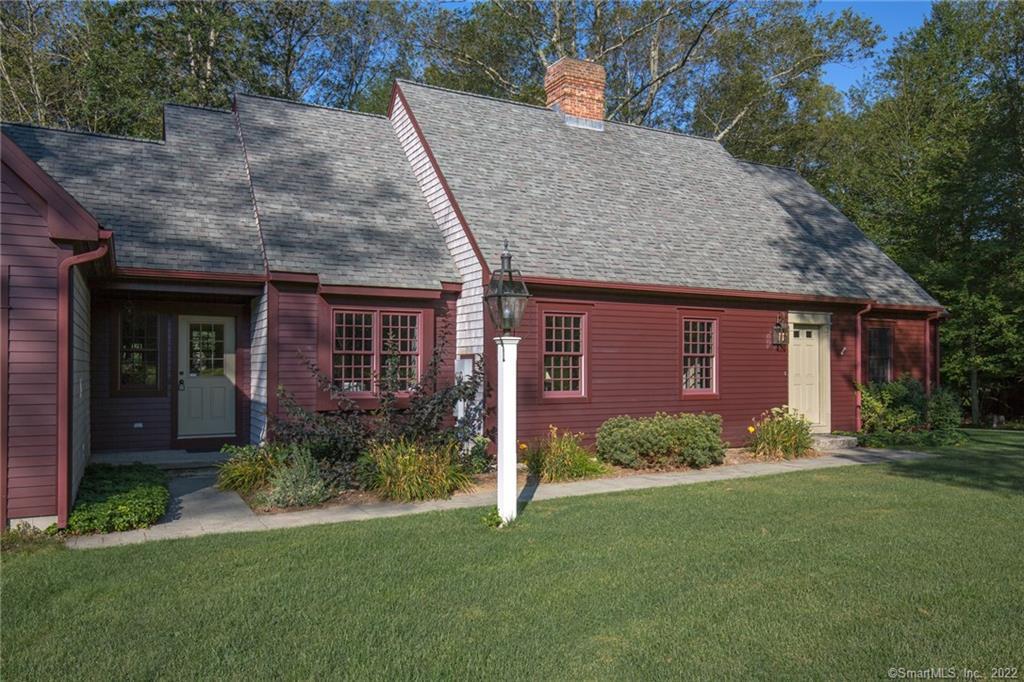 a view of a brick house with a yard potted plants and large tree