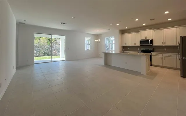 a view of kitchen with kitchen island granite countertop a stove top oven a sink a dining table and chairs