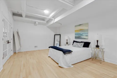a spacious bedroom with a bed and a painting on the wall