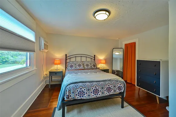 a bedroom with a bed and a dresser next to a window