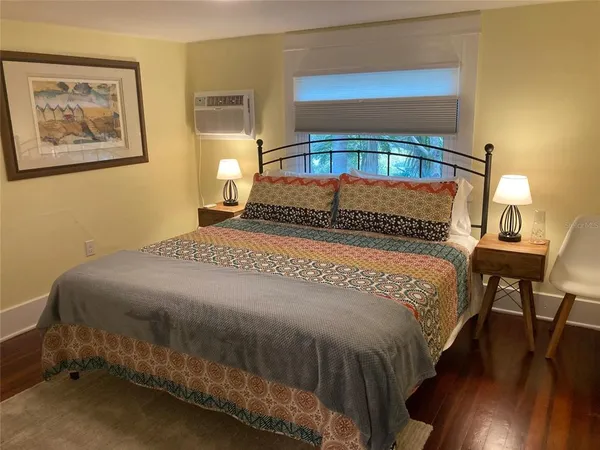 a bedroom with a bed a dresser and wooden floor
