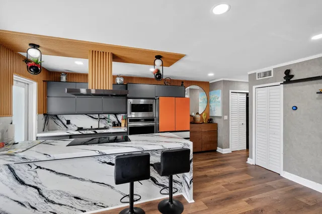 a kitchen with stainless steel appliances kitchen island granite countertop a table chairs in it and wooden floors