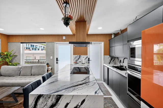 a kitchen with stainless steel appliances granite countertop a refrigerator a sink dishwasher a stove and a dining table with wooden floor