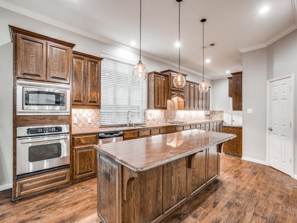 9609 Sam Bass Trail Fort Worth, TX 76244 - Photo 4 of 25 a kitchen with kitchen island a stove a sink a oven and wooden cabinets