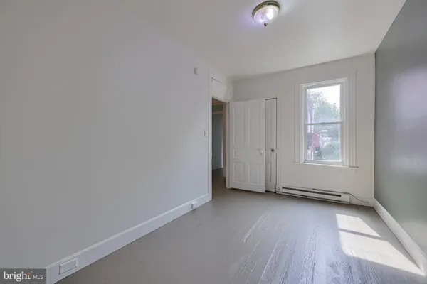 a view of an empty room with wooden floor and windows