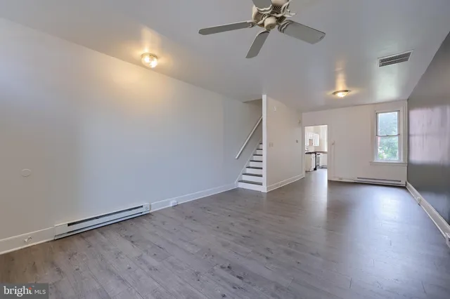 an empty room with wooden floor chandelier and windows