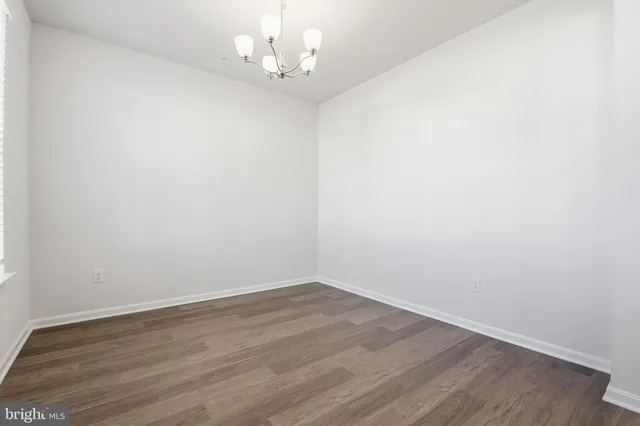 an empty room with wooden floor and chandelier