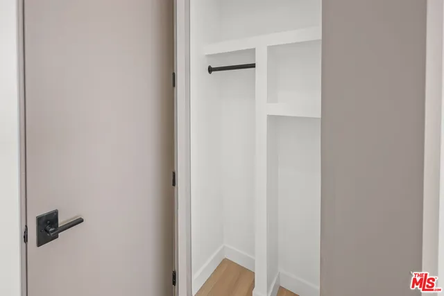 a view of an empty room with wooden floor and closet