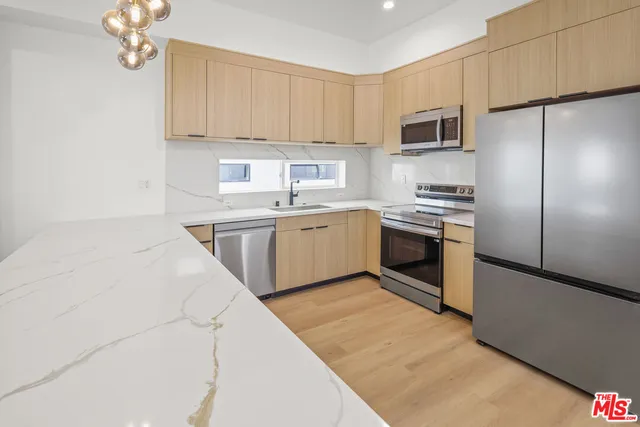 a large kitchen with stainless steel appliances a large counter top and a wooden floor