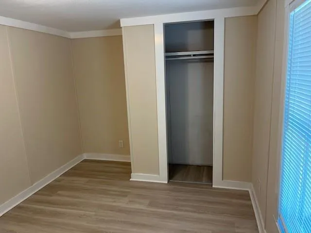 a view of an empty room with wooden floor and closet