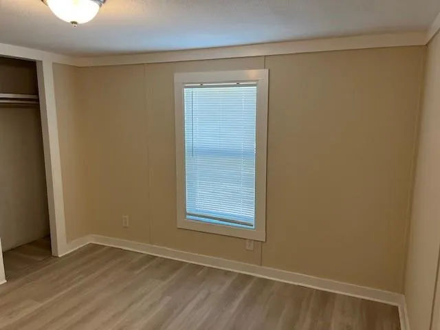 a view of an empty room with wooden floor and a window